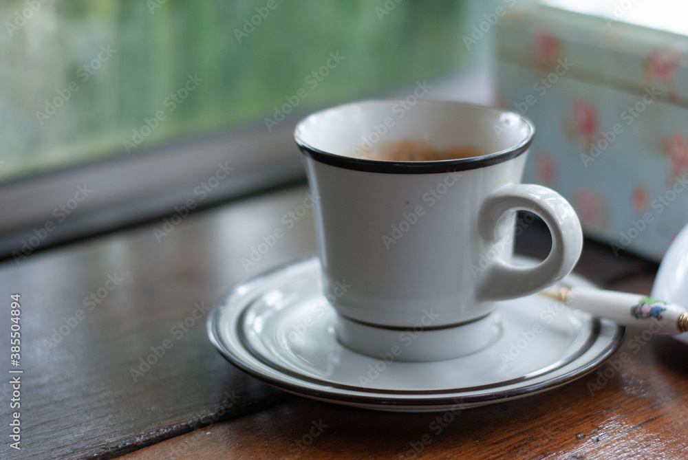 A white ceramic coffee mug with plate in the coffee cafe with chill and relax atmosphere A white ceramic coffee mug with plate in the coffee cafe with chill and relax atmosphere
