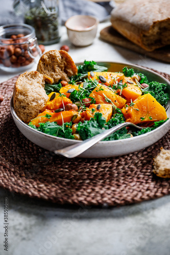 Season salad with grilled pumpkin, kale, chickpea, pepitas and nuts. Autumn vegetarian healthy recipe.