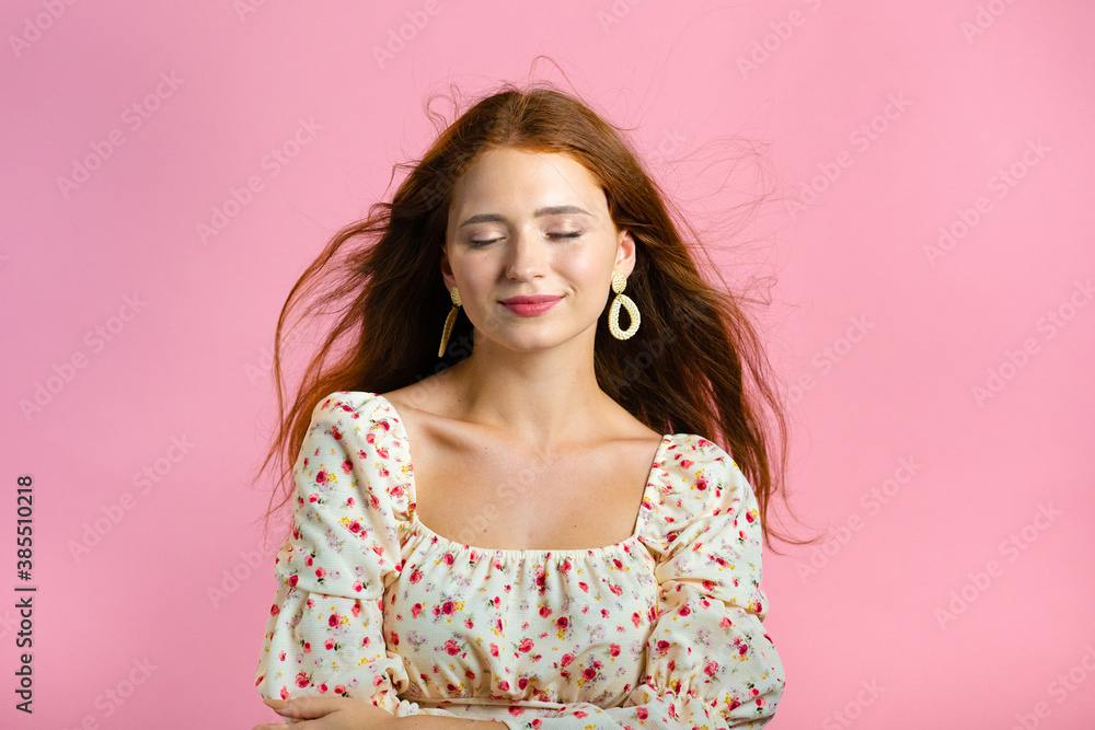 Young woman with long red wavy and shiny hairstyle looking to camera, flirting. Beautiful model girl demonstrate her elegant volume hair. Pink studio background. Young woman with long red wavy and shiny hairstyle looking to camera, flirting. Beautiful model girl demonstrate her elegant volume hair. Pink studio background.