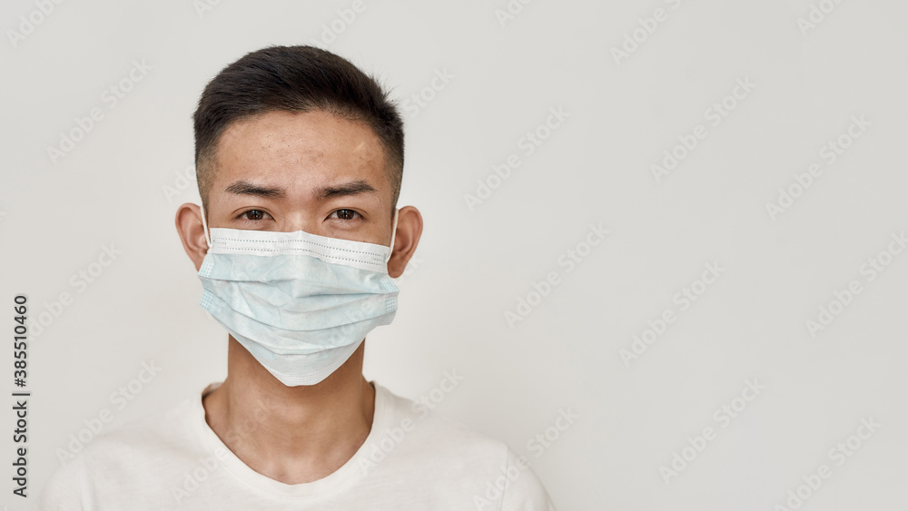 Portrait of young asian man in medical mask looking at camera isolated over white background. Health care, prevention, safety concept Portrait of young asian man in medical mask looking at camera isolated over white background. Health care, prevention, safety concept