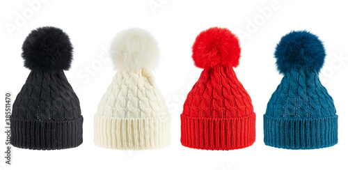 Set of four woolen winter knitted hats of different colors with pompoms, isolated on a white background. Trends of this winter.