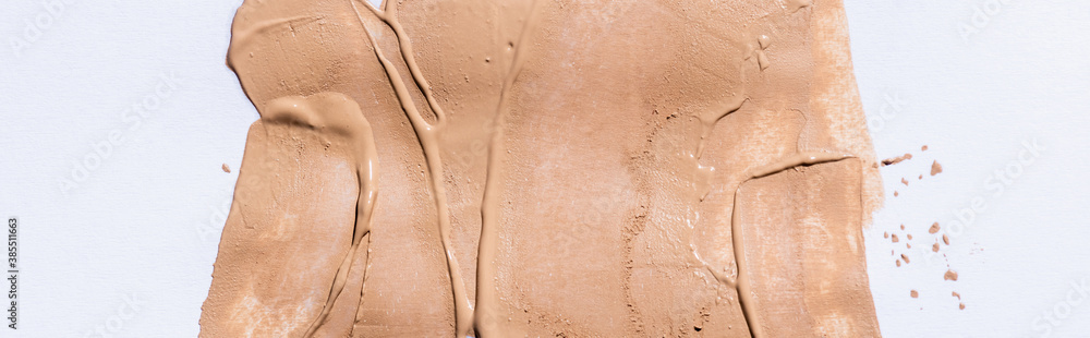 Fototapeta premium top view of beige face foundation brushstrokes on white background, panoramic shot
