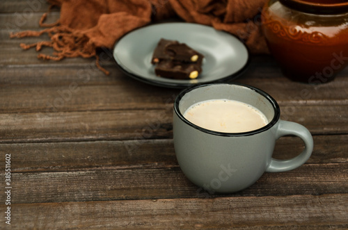 Hot milky drink, dark chocolate as a sweet winter snack.Cup of hot chocolate, pieces of chocolate on the saucer, knitted scarf on the wooden rustic table