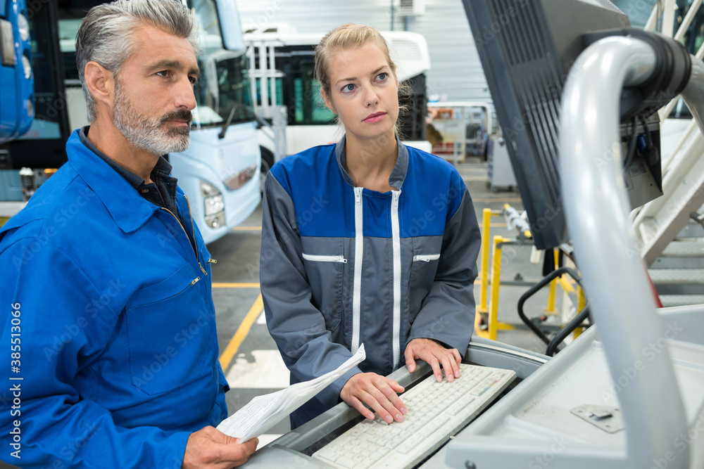 female mechanic using laptop with colleague female mechanic using laptop with colleague