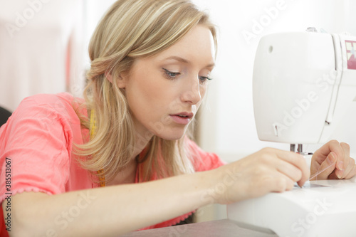 seamstress inserting thread to sewing machine needle