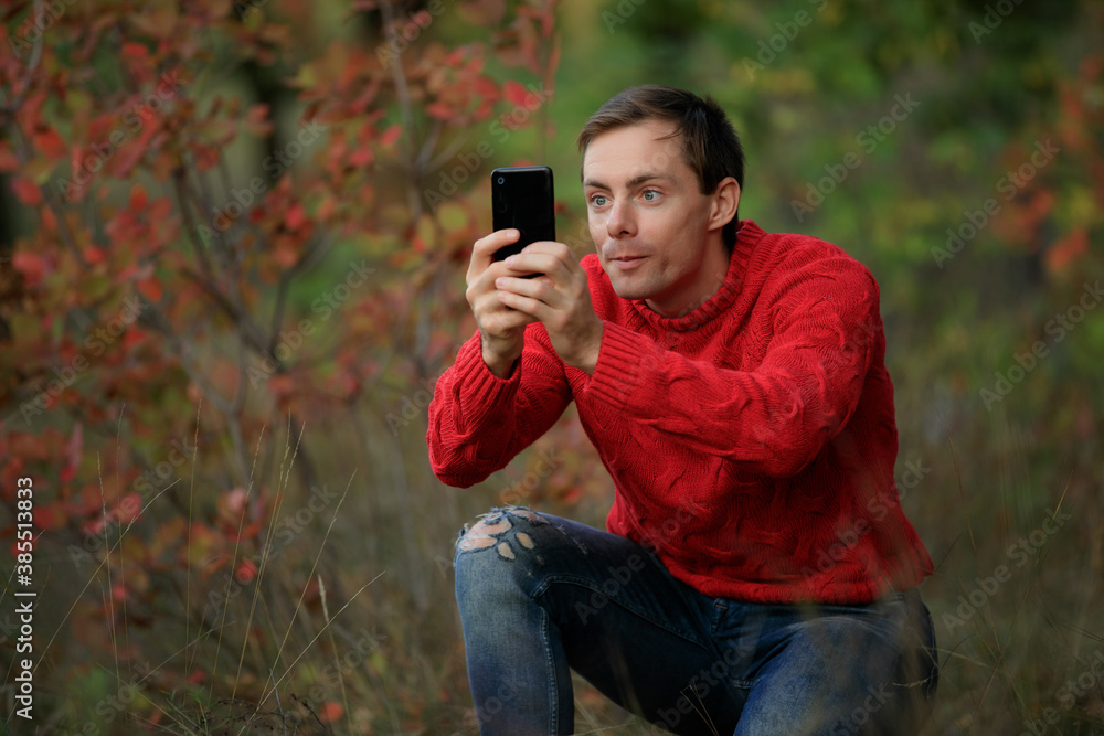 Man in red sweater make a photo by smartphone Man in red sweater make a photo by smartphone