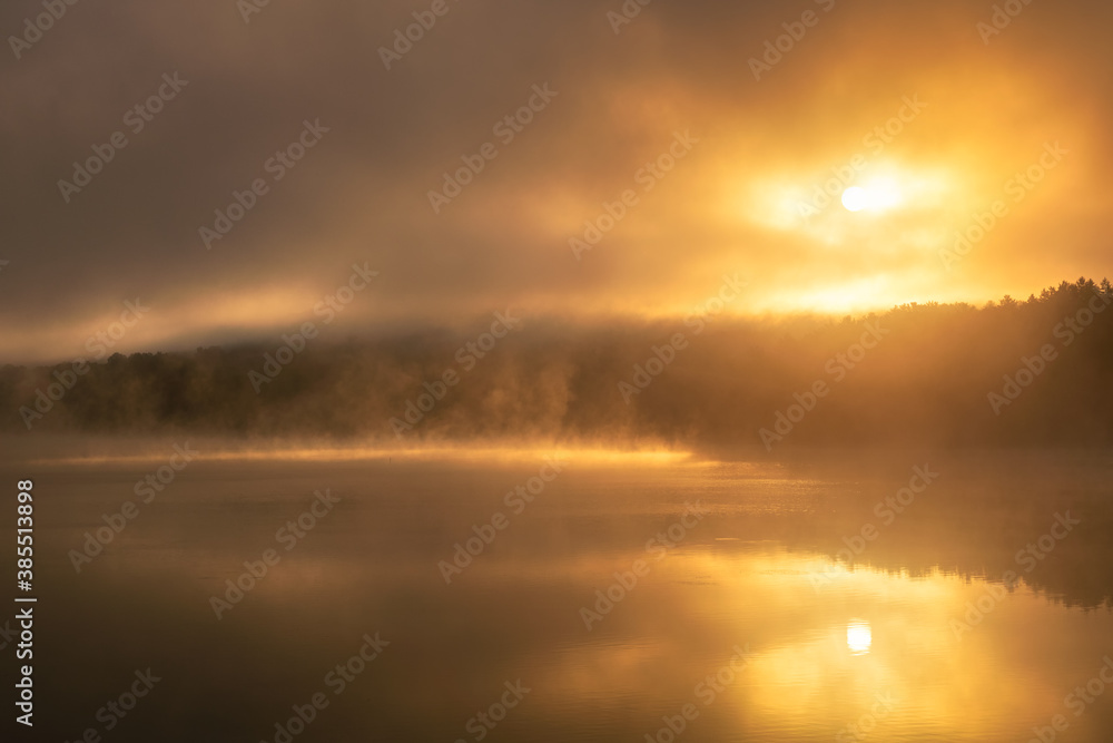 Ethereal moody sunrise with fog and steam being illuminated over a lake, as a bird flies across the water. Croton Gorge Park New York. Ethereal moody sunrise with fog and steam being illuminated over a lake, as a bird flies across the water. Croton Gorge Park New York.