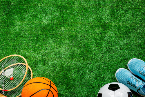 Sport games equipment on football field - balls, sneakers, rackets. Top view