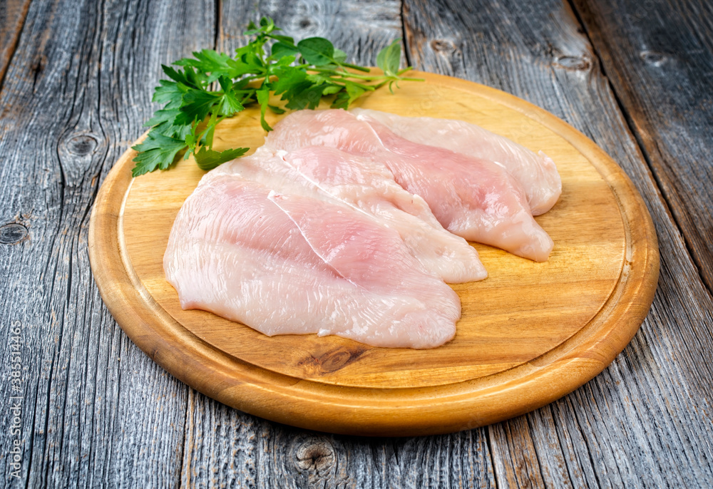 Rohes traditionelles Hänchen Schnitzel mit Kräuter angeboten als close-up auf einem rustikalen Holz Board mit Textfreiraum Rohes traditionelles Hänchen Schnitzel mit Kräuter angeboten als close-up auf einem rustikalen Holz Board mit Textfreiraum