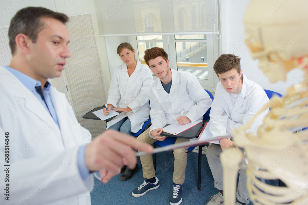 Obraz premium Teacher pointing to skeleton while giving lecture to students