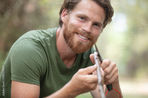 cheerful male tourist preparing wood