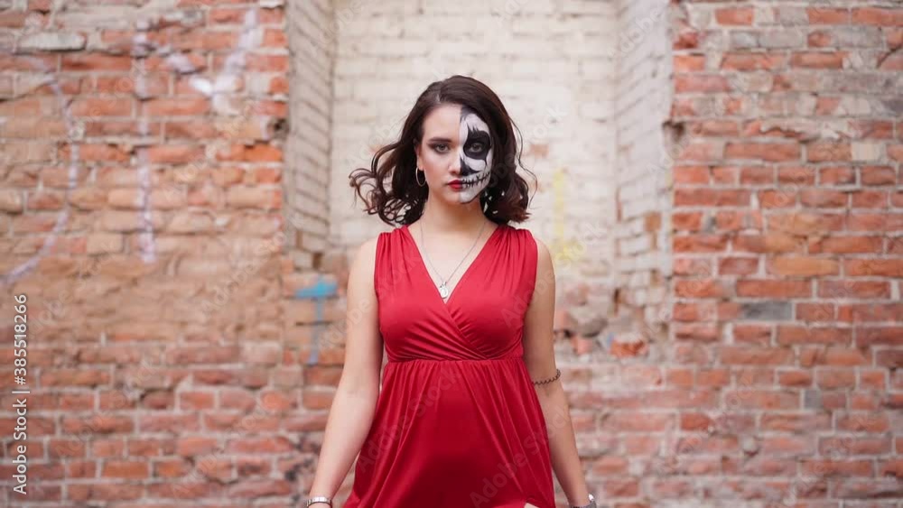 Beautiful sexy woman in a red evening dress with makeup on Halloween goes against the backdrop of an abandoned building. A terrible holiday and night of October 31st. Slow motion Beautiful sexy woman in a red evening dress with makeup on Halloween goes against the backdrop of an abandoned building. A terrible holiday and night of October 31st. Slow motion