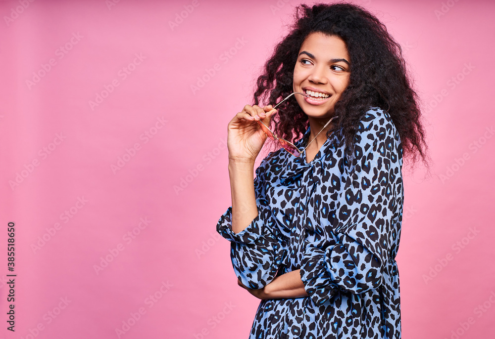 A positive dark-skinned lady looks to the side on a pink background. A positive dark-skinned lady looks to the side on a pink background.