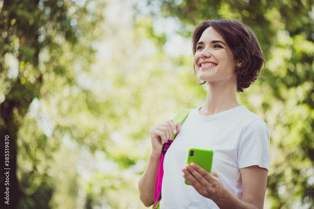 Photo of charming lovely cute lady cheerful look hands hold telephone blogging live channel translate beautiful forest tree view share video subscribers wear white shirt outside