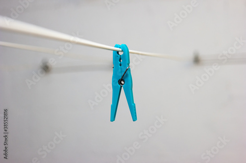 Light blue plastic laundry clip on a hanging wire indoor isolated shallow depth of field