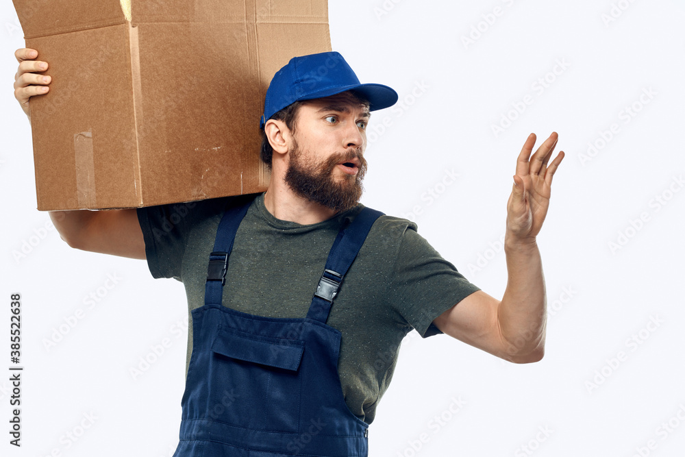 A man in a working uniform with a box in his hands delivery transportation work A man in a working uniform with a box in his hands delivery transportation work