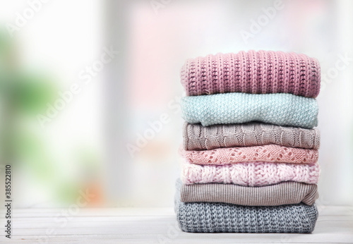 Stack of knitted textured clothing on table.Colorful winter clothes,warm apparel.Heap of knitwear. photo