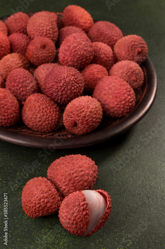Fresh Lychees on a plate close-up, on a dark green background.