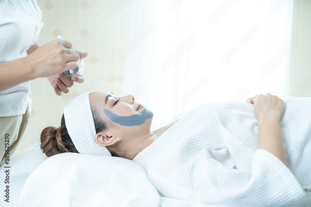Facial Spa. Face Skin Care. An Asian woman is masking her face in a spa salon. Hand holding a brush. Facial Spa. Face Skin Care. An Asian woman is masking her face in a spa salon. Hand holding a brush.