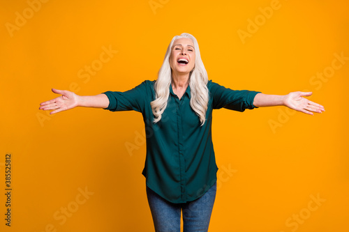 Hug me Photo of cheerful white haired grandma lady spread open arms meet grandchildren airport bus train station wear green shirt jeans isolated vivid yellow color background