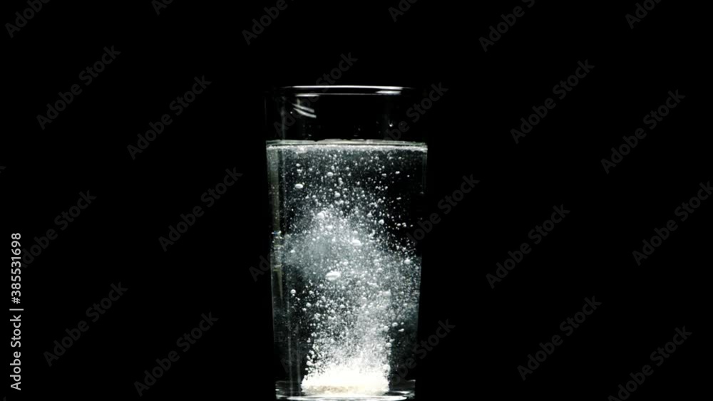 White Effervescent dissolving aspirin pill drops into glass of water