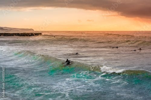 Sunset at Ericeira beach with surfers in the water, Portugal