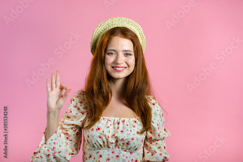 Cute woman showing thumb up sign over pink background. Positive young girl smiles to camera. Winner. Success. Body language.