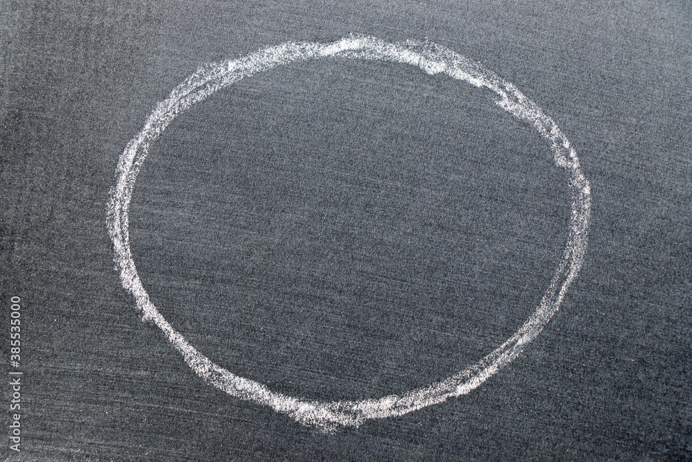 White color chalk hand drawing in circle or oval shape on black board background