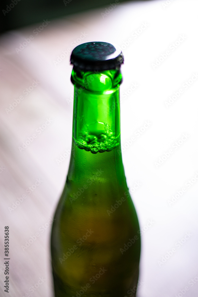 Blond beer on a green bottle closed on a wooden background Blond beer on a green bottle closed on a wooden background