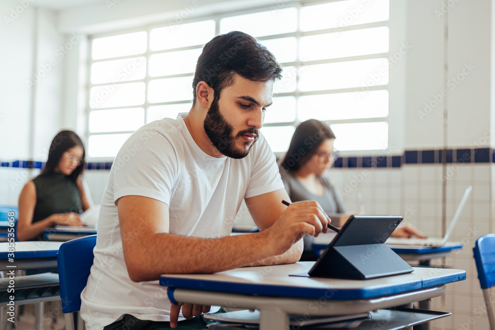 Fototapeta premium College student sitting at the desk using digital tablet