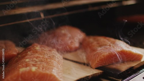 smoked salmon filets on little wooden planks roasting on a grill steaming and are ready to be eaten