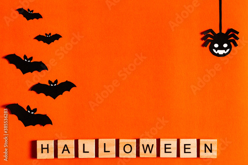 Halloween lettering on orange background with black paper silhouettes, bats, pumpkin, spider. The Concept Of Halloween. the view from the top