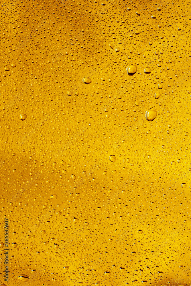 Close up view of cold drops on the glass of beer background. Texture of cooling alcohol drink with macro bubbles on the glass wall. Fizzing or floating up to top of surface. Golden colored. Close up view of cold drops on the glass of beer background. Texture of cooling alcohol drink with macro bubbles on the glass wall. Fizzing or floating up to top of surface. Golden colored.