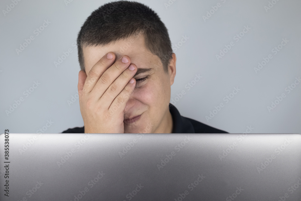 The man looks at the laptop, is embarrassed and ashamed of what he saw there. Expressing emotions and reacting to what you see on the Internet. Shocking content concept. The man looks at the laptop, is embarrassed and ashamed of what he saw there. Expressing emotions and reacting to what you see on the Internet. Shocking content concept.