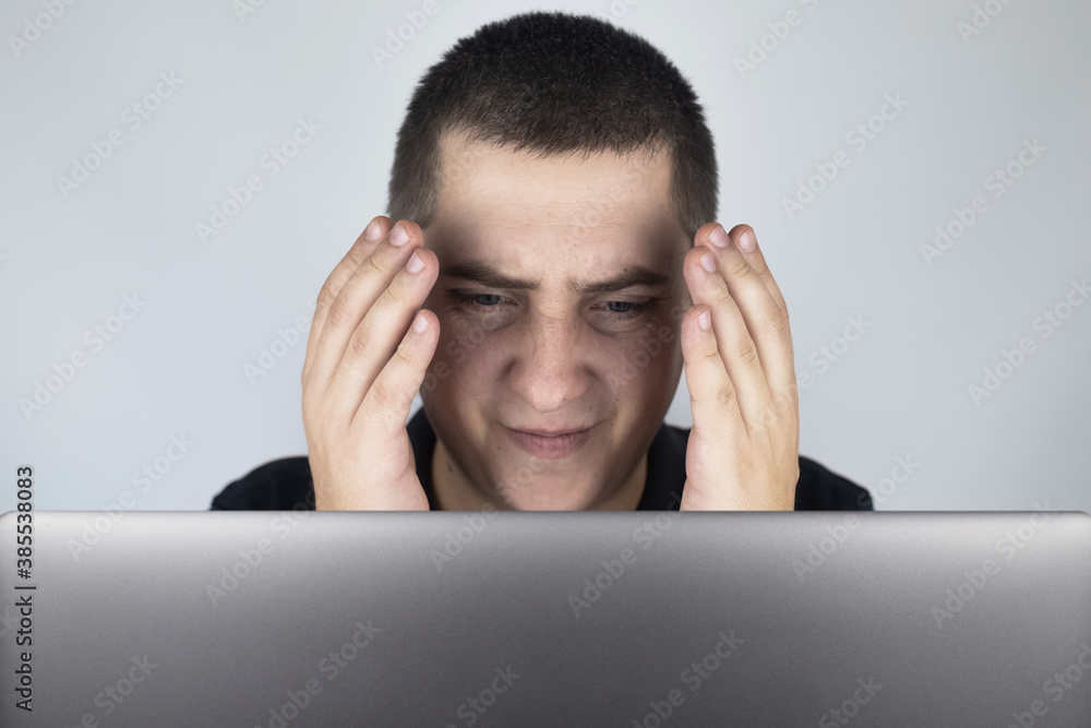 The man looks at the laptop, is embarrassed and ashamed of what he saw there. Expressing emotions and reacting to what you see on the Internet. Shocking content concept. The man looks at the laptop, is embarrassed and ashamed of what he saw there. Expressing emotions and reacting to what you see on the Internet. Shocking content concept.