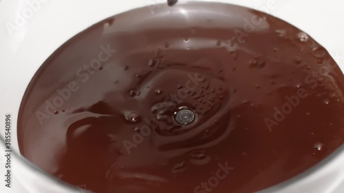 chocolate chips or couverture callets fall in bowl of melted dark chocolate slow mo. Advertising for handcrafted confectionary shop. Culinary Video Blog. Homemade sweeties production