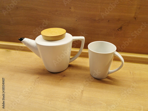 Teapot and white mug on a wooden table. Kitchenware concept