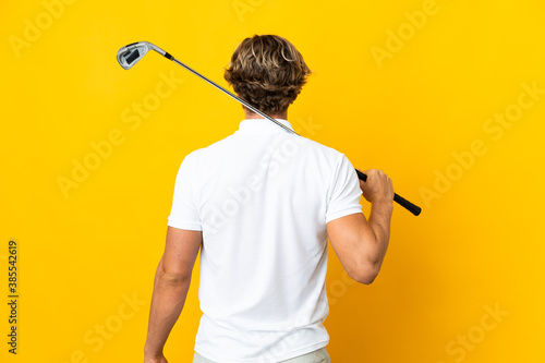 English man over isolated white background playing golf and in back position