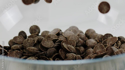 chocolate chips or couverture callets fall in glass bowl slow mo. Ingredients for premium handmade chocolate. Preparing desserts, candies or truffles. Cooking video blog instructions for home sweets