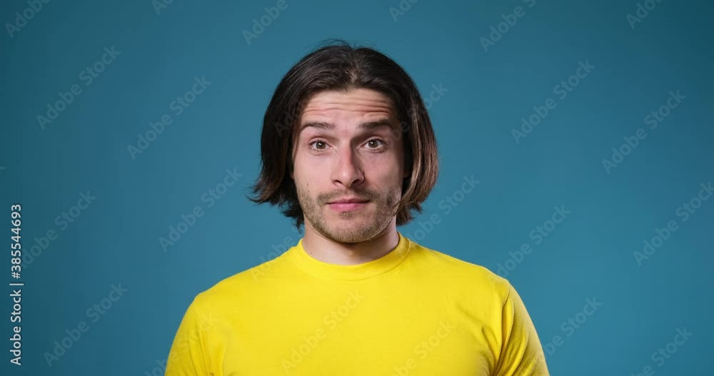 Confused man looking with raised eyebrow over blue background Confused man looking with raised eyebrow over blue background