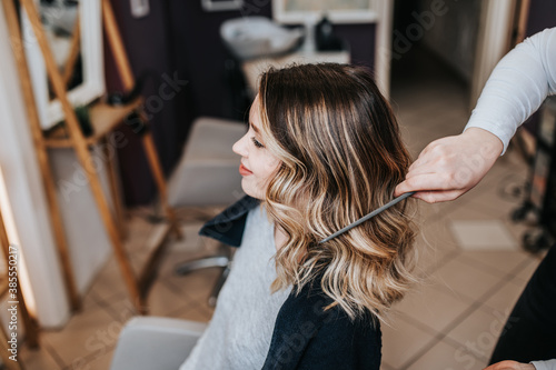 Beautiful hairstyle of young woman after dyeing hair and making highlights in hair salon.