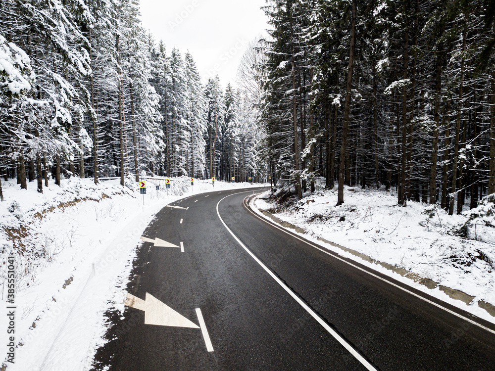 Winding road through the forest, from high mountain pass, in winter time. Aerial view by drone. Romania Winding road through the forest, from high mountain pass, in winter time. Aerial view by drone. Romania