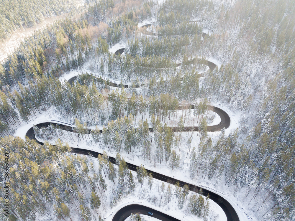 Winding road through the forest, from high mountain pass, in winter time. Aerial view by drone. Romania Winding road through the forest, from high mountain pass, in winter time. Aerial view by drone. Romania