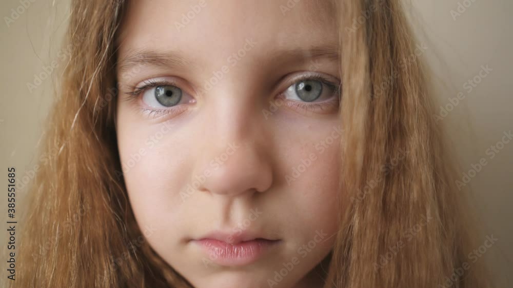 Close up female face of desperate child looking into camera indoor. Disappointed gaze of small upset kid. Portrait of little blonde girl with sorrowful expression inside Close up female face of desperate child looking into camera indoor. Disappointed gaze of small upset kid. Portrait of little blonde girl with sorrowful expression inside