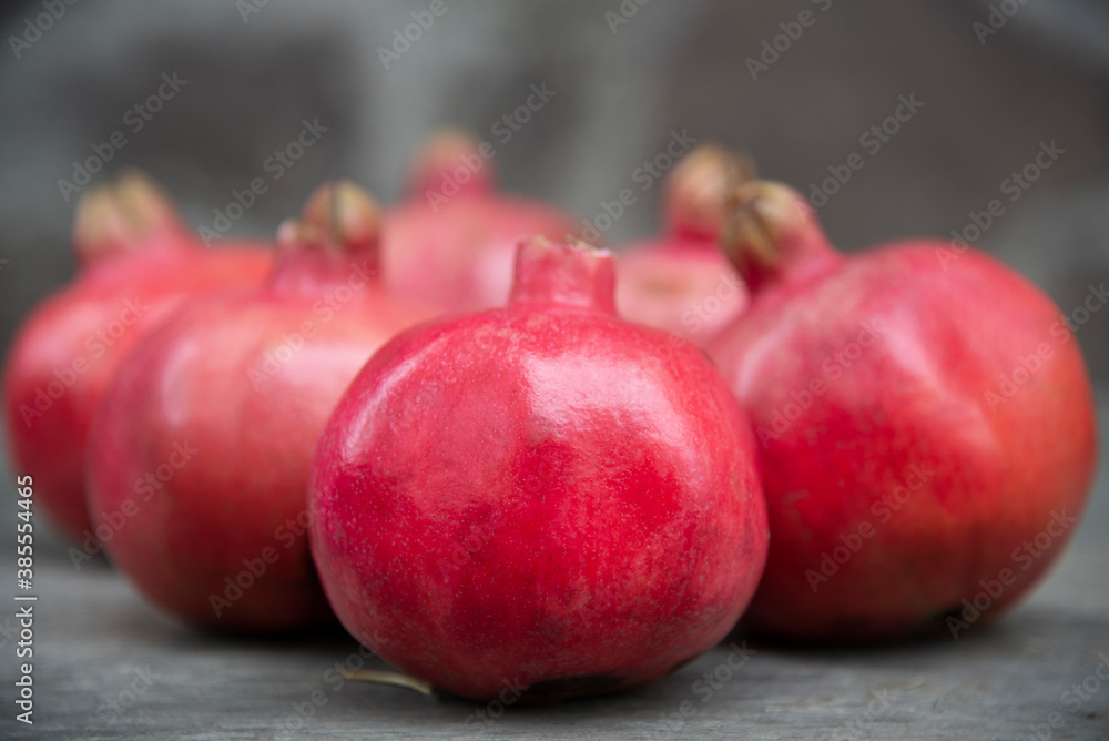 Red whole grenades against the blurred  background of pomegranates  and stone wall