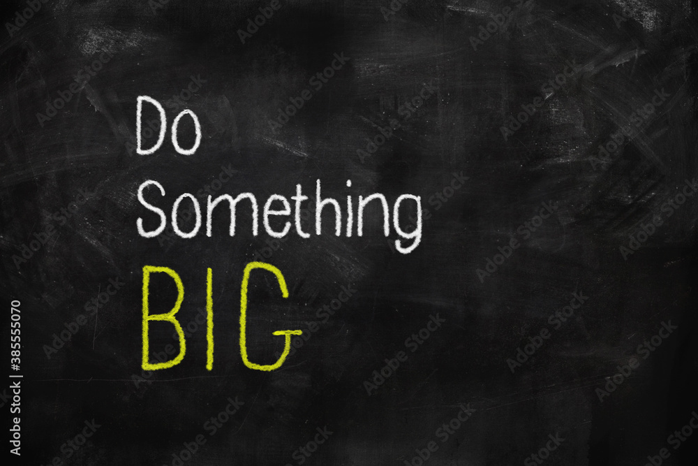 Do something big written with white and yellow chalk on blackboard Do something big written with white and yellow chalk on blackboard