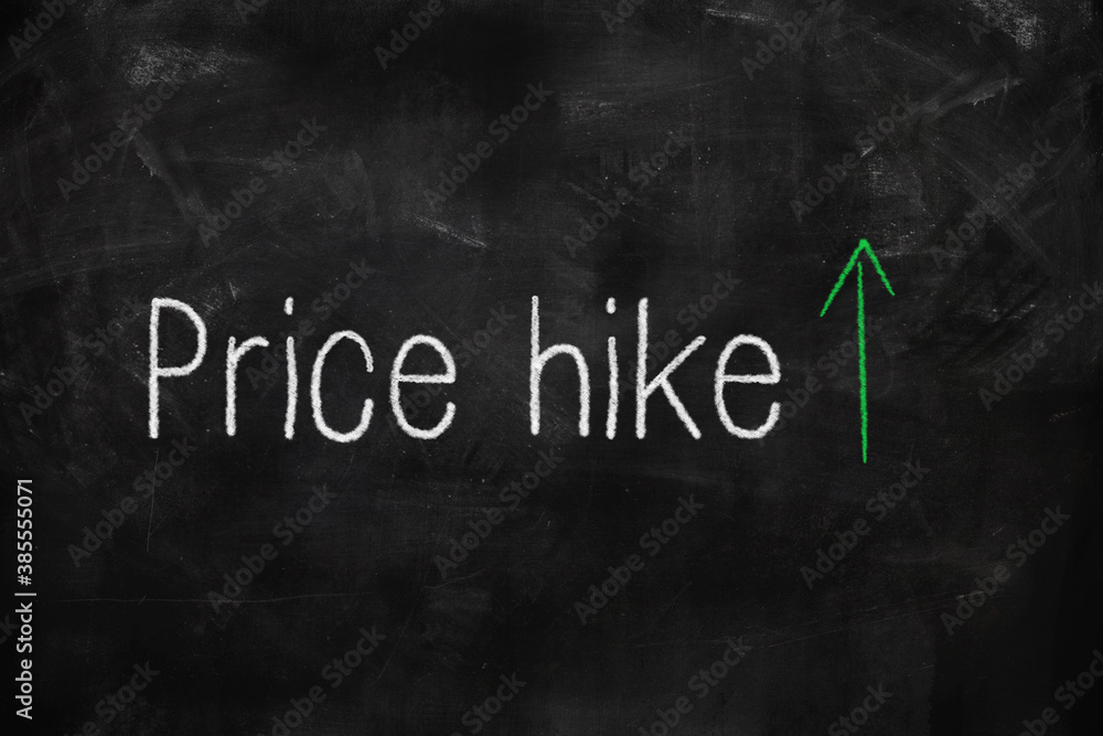 Price hike written with white and green chalk on blackboard in classroom Price hike written with white and green chalk on blackboard in classroom