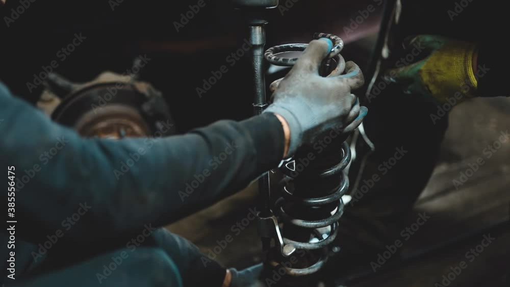 Auto mechanics compress the spring with zip ties to replace the shock absorber. Car suspension repair. Auto mechanics compress the spring with zip ties to replace the shock absorber. Car suspension repair.