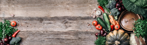 Copper pot, herbs, purple onion, pumpkin, tomato, broccoli, pepper, cabbage, carrot, parsley, calafior, zucchini on wooden background. Top view. Copy space. Banner. Autumn harvest food cooking concept photo