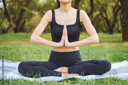 Close up of young attractive woman doing yoga in lotus position in the park © Artem